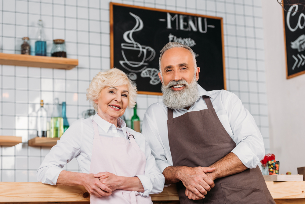 two middle=aged business owners standing at their coffee chop counter.