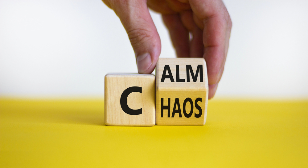 a person's hand is turning a word cube from "chaos" to "calm".